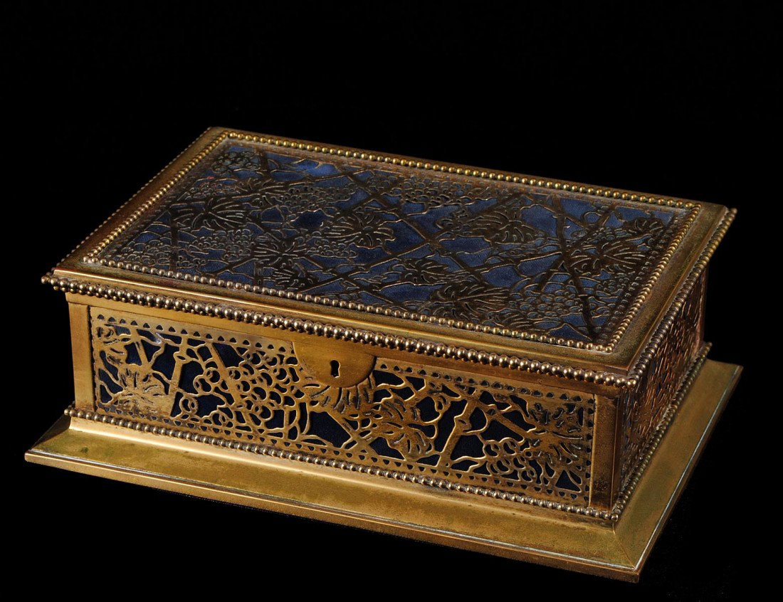 TIFFANY STUDIOS GILT BRONZE JEWELRY BOX: American. Circa 1925. Stamped Tiffany Studios 830. In the "Grapevine" pattern. Length 9 3/8". (Cond: glass missing)