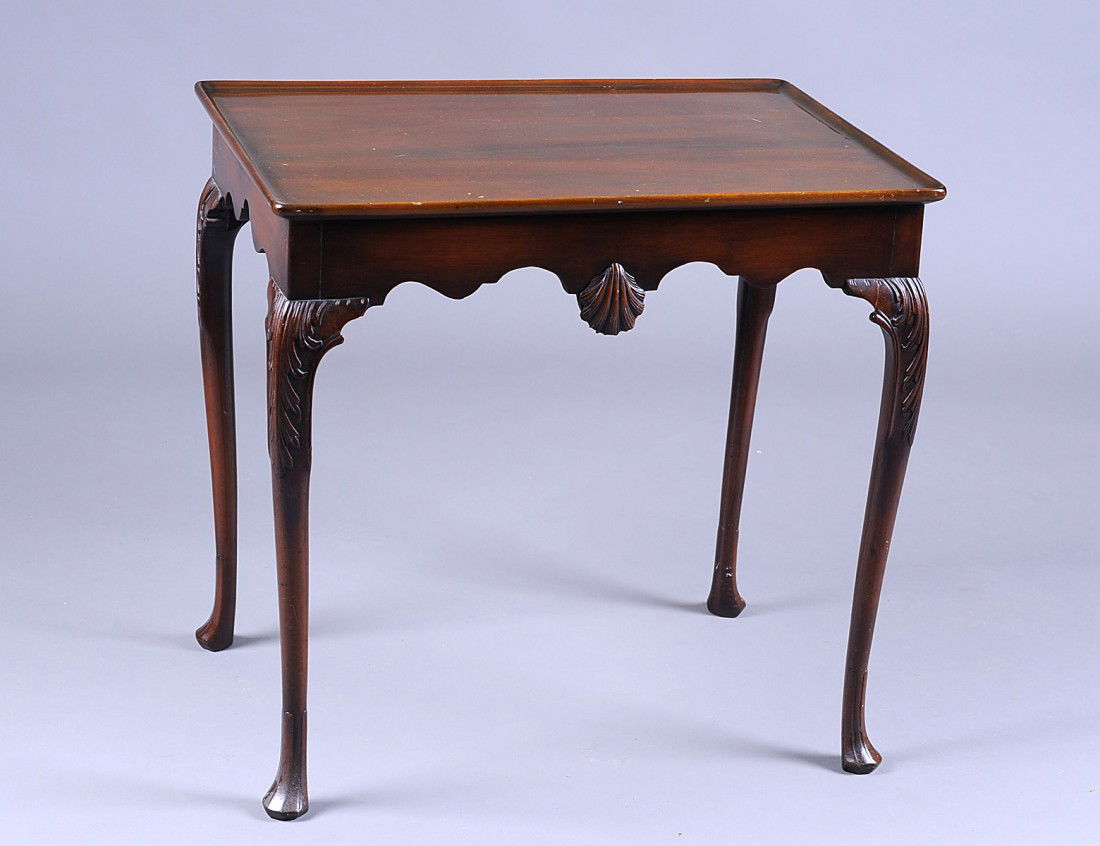 GEORGE III/IV MAHOGANY TEA TABLE: The rectangular tray form top above the scalloped frieze carved with a shell, raised on cabriole legs ending in pad feet. Height 28”. Width 21 ¼”. Depth 29 ½”. (800/1200)