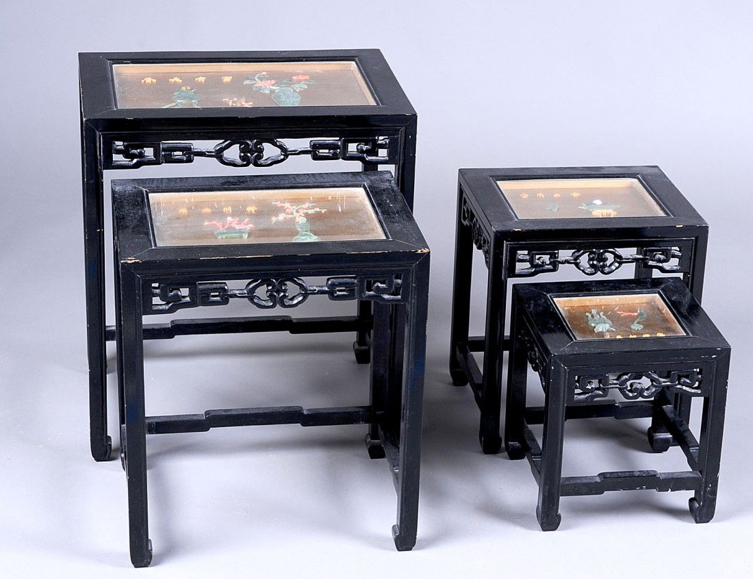 NEST OF FOUR TEAKWOOD TABLES: Each inset with a glass covered panel containing carved hardstone flower-filled pots, jardinières and calligraphy. Height of tallest 23”. Width 20”. Depth 14”. (200/300)