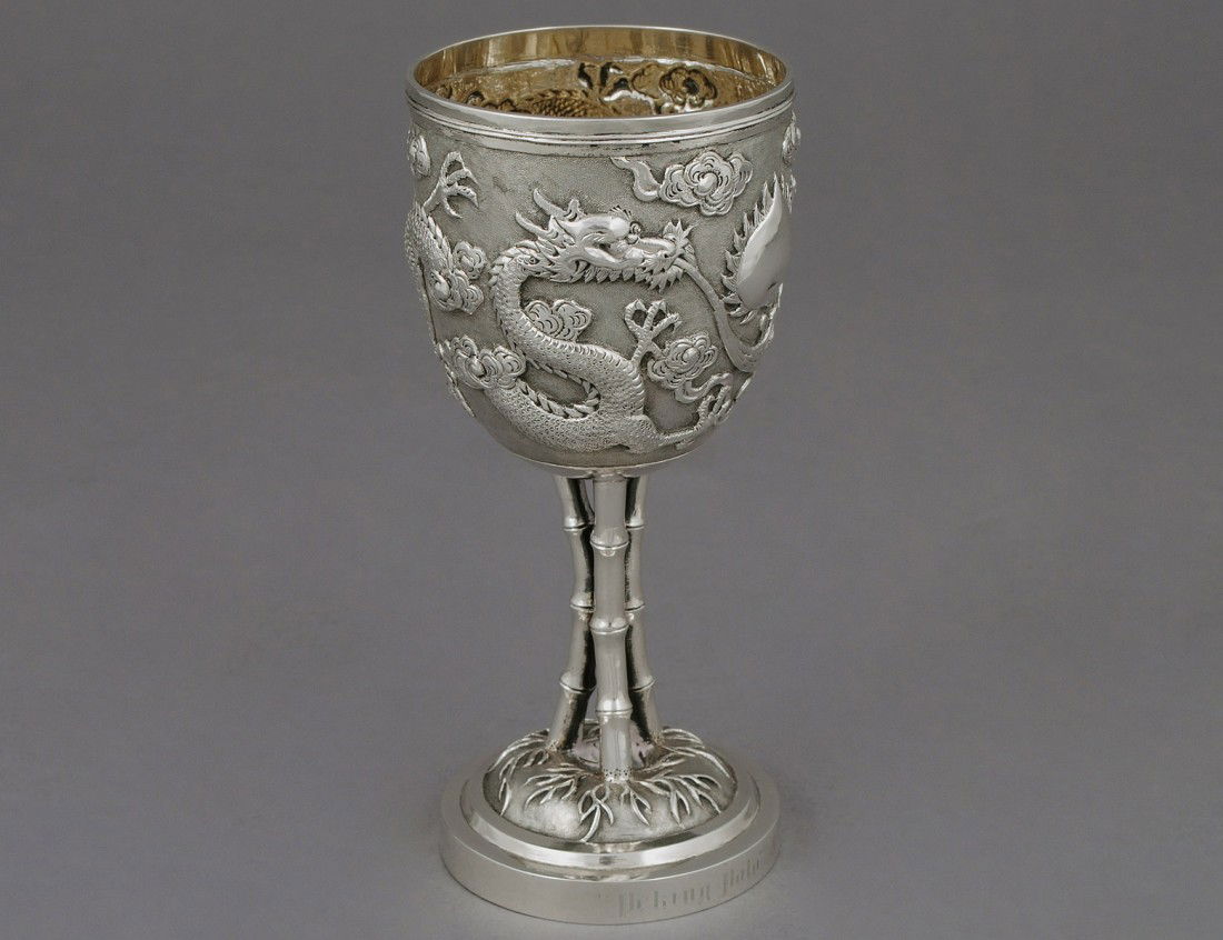 EXPORT SILVER CUP: Chinese. Hong Kong. 19th Century. Maker TC. The bowl chased in relief with dragons supported by bamboo form legs on a circular base. Height 5 3/4". (1500/2000)