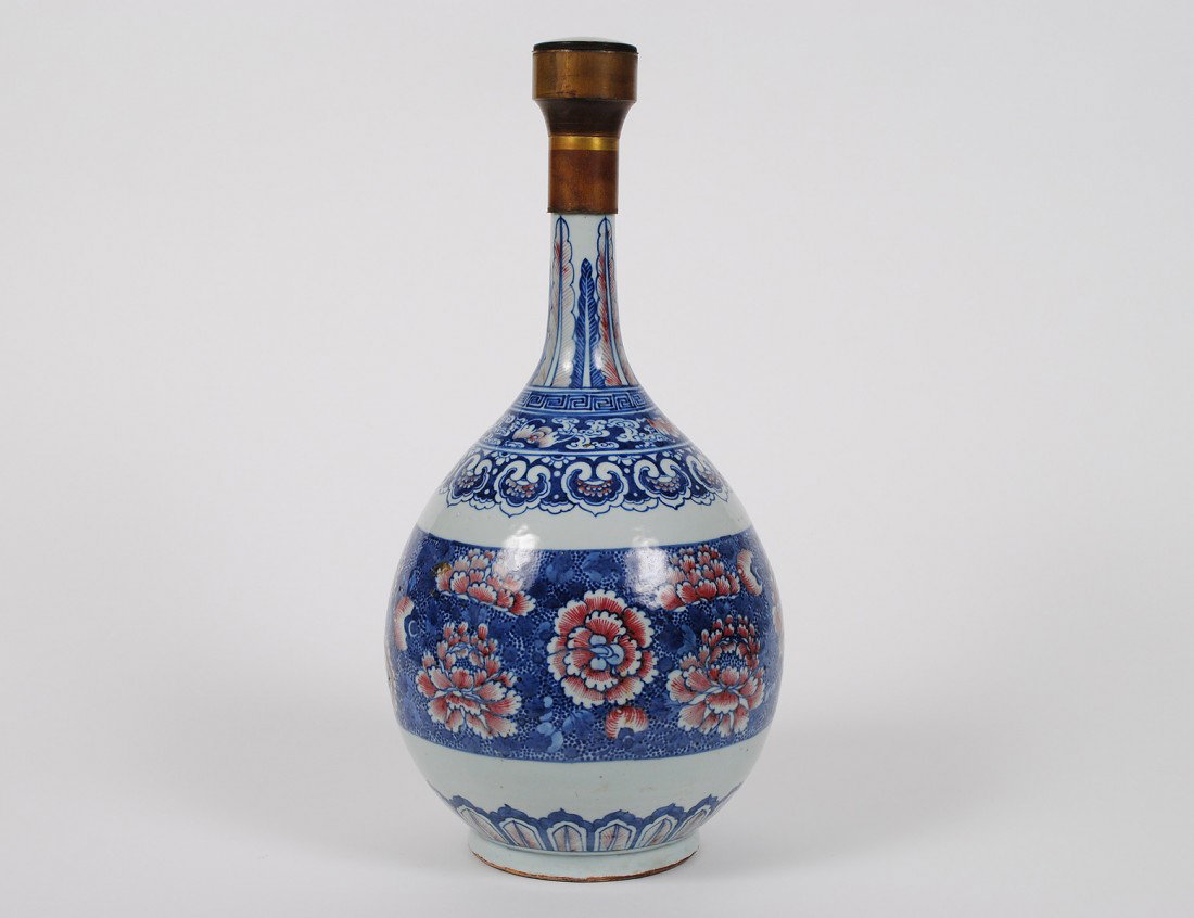 COPPER RED GLAZED PORCELAIN VASE: Chinese. 18th Century. Of bottle form decorated with chrysanthemums, ferns, bats and lappets. Height 17 ¼”. Drilled on the underside for a lamp. (500/700)