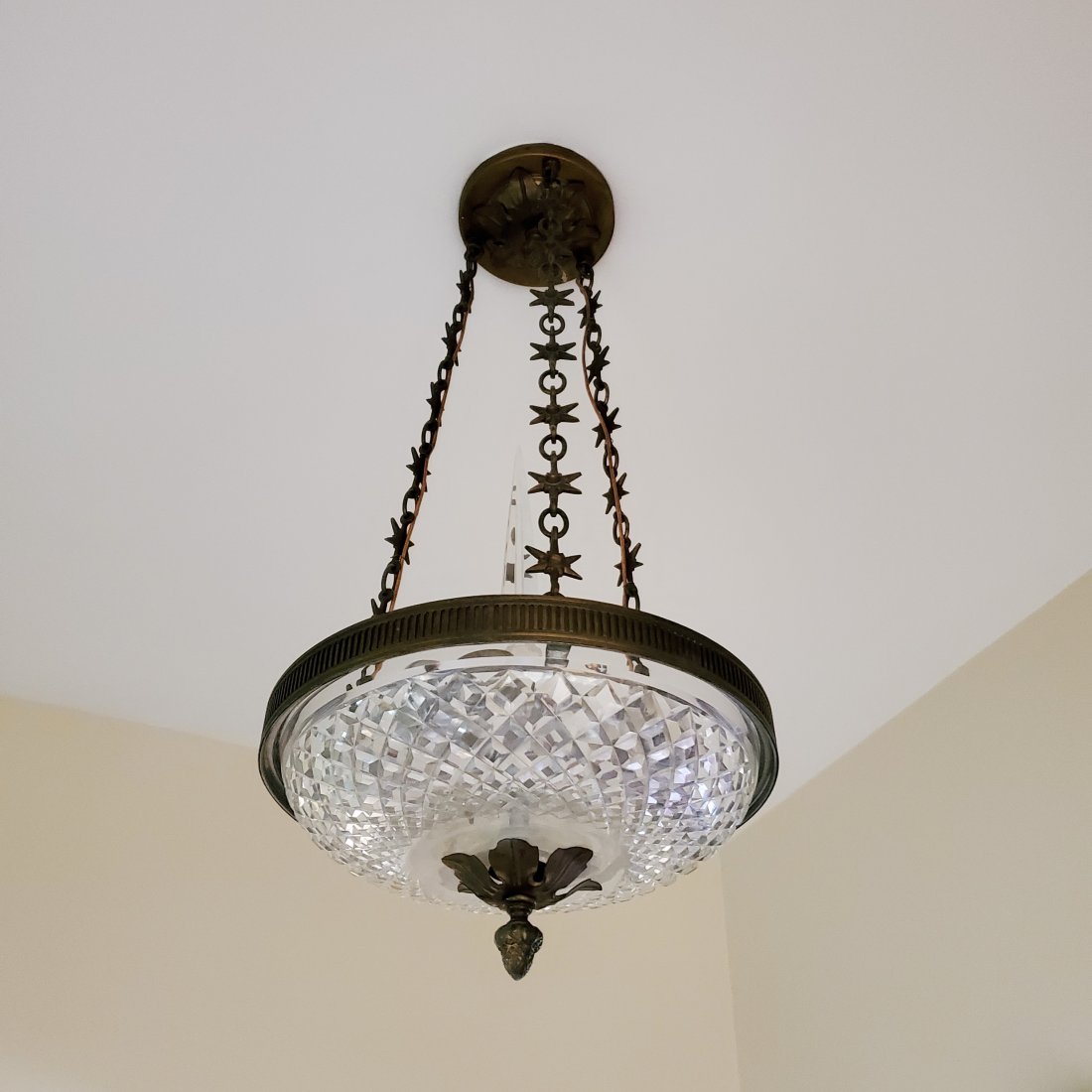 Pair of Three Light Empire Style Cut Glass and Brass Pendant Lighting Fixtures: 20th Century, the cut glass plafonnier with acorn drop finial and suspended by three chains with tiered stars, 24" h. 10 1/2" dia.