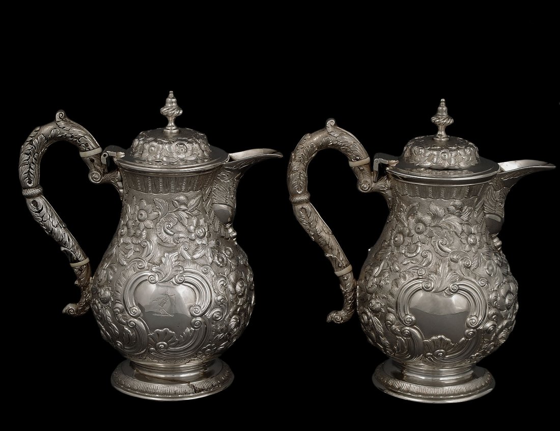 PAIR OF WILLIAM IV STERLING SILVER JUGS: Irish. Dublin. 1836. Maker: R. Smith. Each of baluster form, chased with a hunting scene on one side and flowers surrounding a shield on the other. Height 9 3/4". (88 oz) (10000/15000)