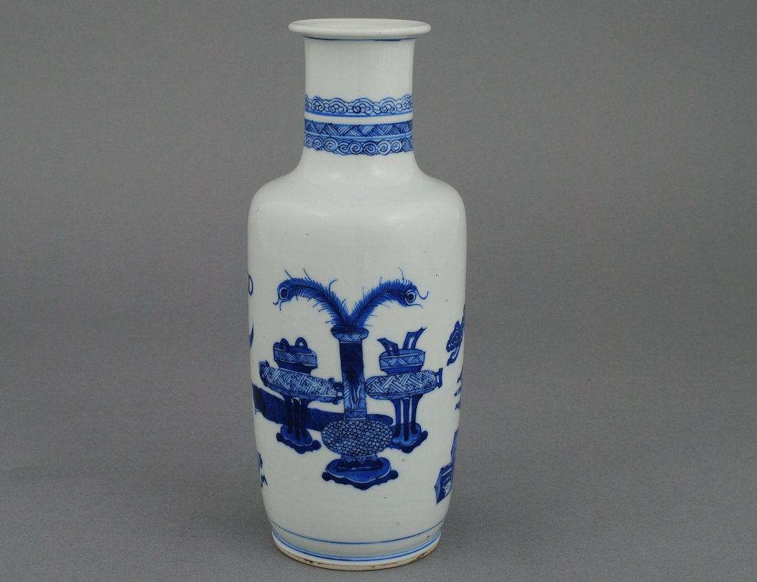 FINE BLUE AND WHITE PORCELAIN VASE: Chinese. Kangxi Period. 1662-1722. Of rouleau shape, painted with precious objects. Height 9 1/4". (Cond: minor chip to underside of foot rim) (2500/3500)