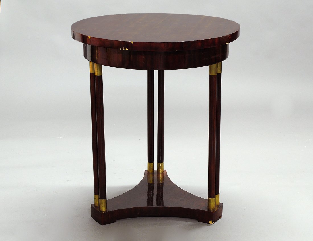 BIEDERMEIER MAHOGANY VENEERED CIRCULAR SIDE TABLE: Austrian. 19th Century. The circular top supported by six rounded posts with brass capped ends, raised on a tripartite base. Height 30 5/8". Diameter 26 1/4". (Cond: some loss to veneer) (500/700)