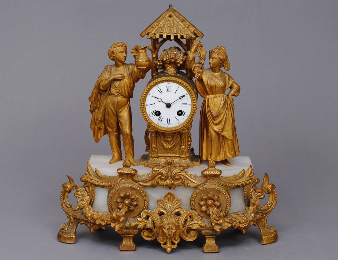GILT BRONZE AND ONYX MANTEL CLOCK: European. The well shaped case flanked by a man and a maiden raised on the onyx base with gilt bronze mounts. Height 16". (Cond: crystal missing from dial and rear) (1000/1500)
