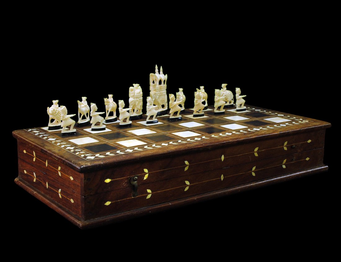 CARVED IVORY CHESS SET: Indian. Both sets natural, one with painted bases, king and queen seated in hodah on top of elephants. Height of king 3 1/8". Height of pawn 1 1/2". With ivory inlaid board box. (400/600)
