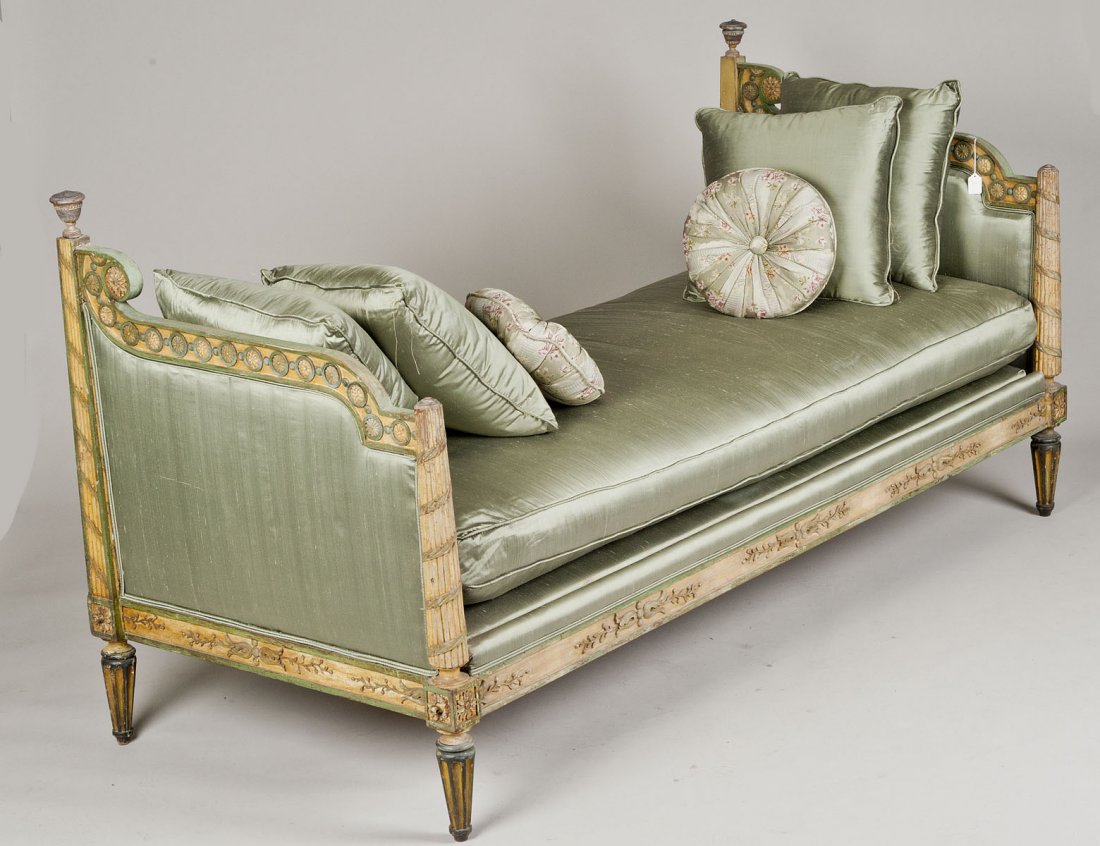 NEO-CLASSICAL CARVED AND PAINTED DAYBED: Italian. 18th Century. With rectangular loose seat cushion above the foliate carved front rail, flanked by shaped upright arms with ribbon tied fluted terminals, raised on short circular reeded legs. 