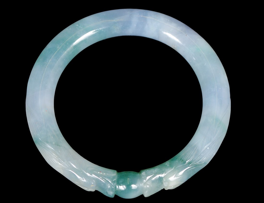 PALE GREEN JADE BANGLE: Chinese. In the form of two dragons joined by a ball. (250/350) Note: This lot is being re-offered for sale due to the fact that Kat Yung Lok of 140-30 Ash Ave, Flushing, New York failed to honor his