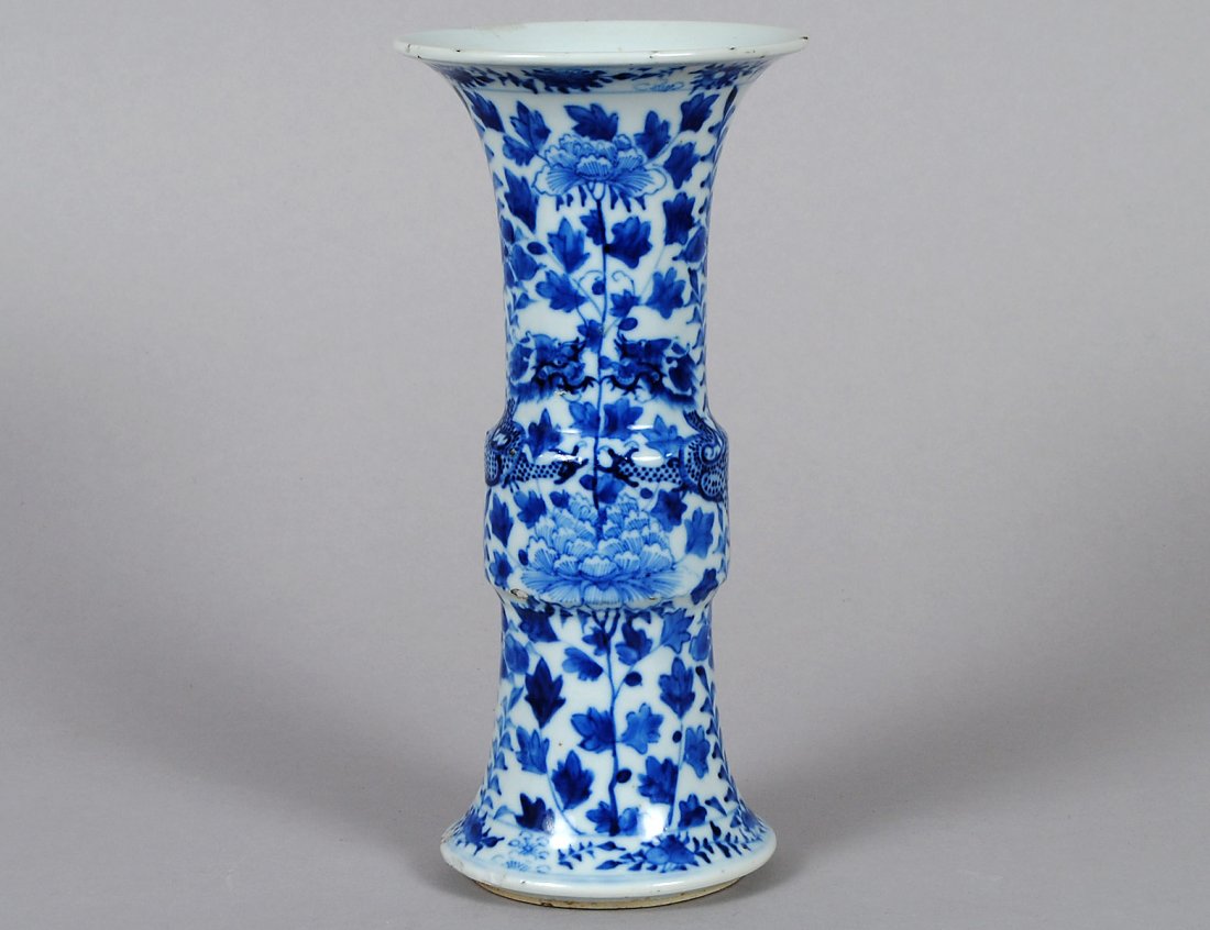 BLUE AND WHITE PORCELAIN VASE: Chinese. Four character Kangxi mark and of the period. 1662-1722. Of beaker form enameled with dragons among foliage. Height 9 3/4". (Cond: minor chips to foot and minute chips to glaze at mouth) (500
