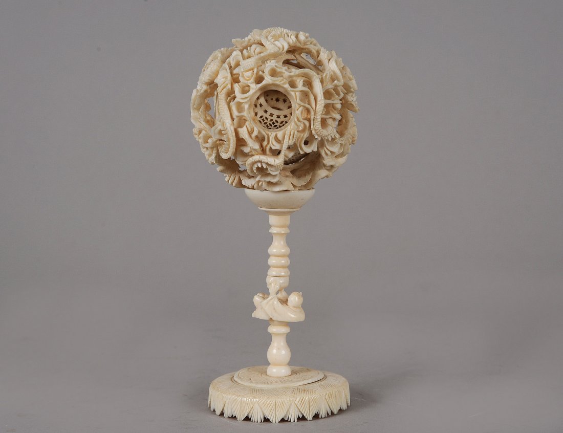 CARVED IVORY CONCENTRIC BALL AND STAND: Chinese. Composed of nine inner balls, carved with a dragon. Height 6". (250/350)