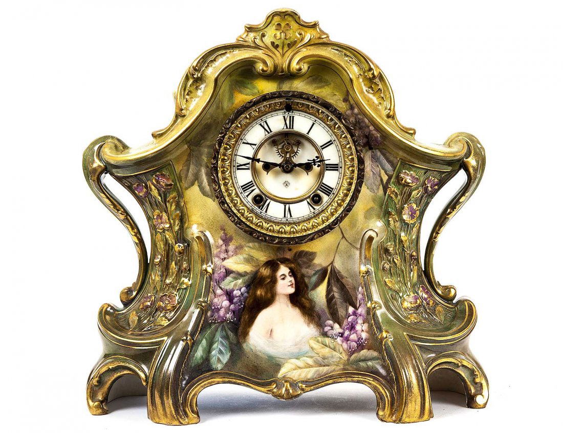 ANSONIA FAIENCE MANTEL CLOCK: The American movement housed in a German faience case, painted with a maiden and impressed with “La Larjon”. Height 14 ¼”. (400/600)
