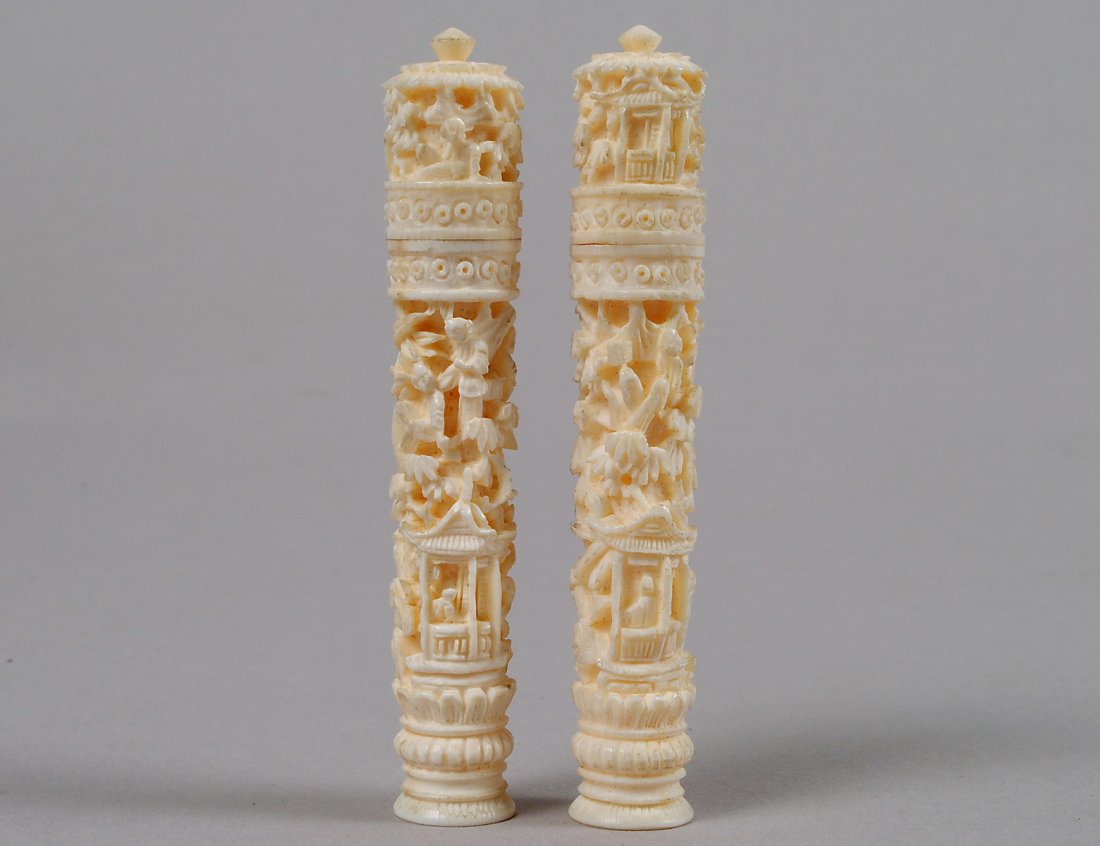 PAIR OF CARVED IVORY NEEDLE CASES: Chinese. Each of columnar shape carved in the round with a village scene. Height 3 3/8”. (200/300)