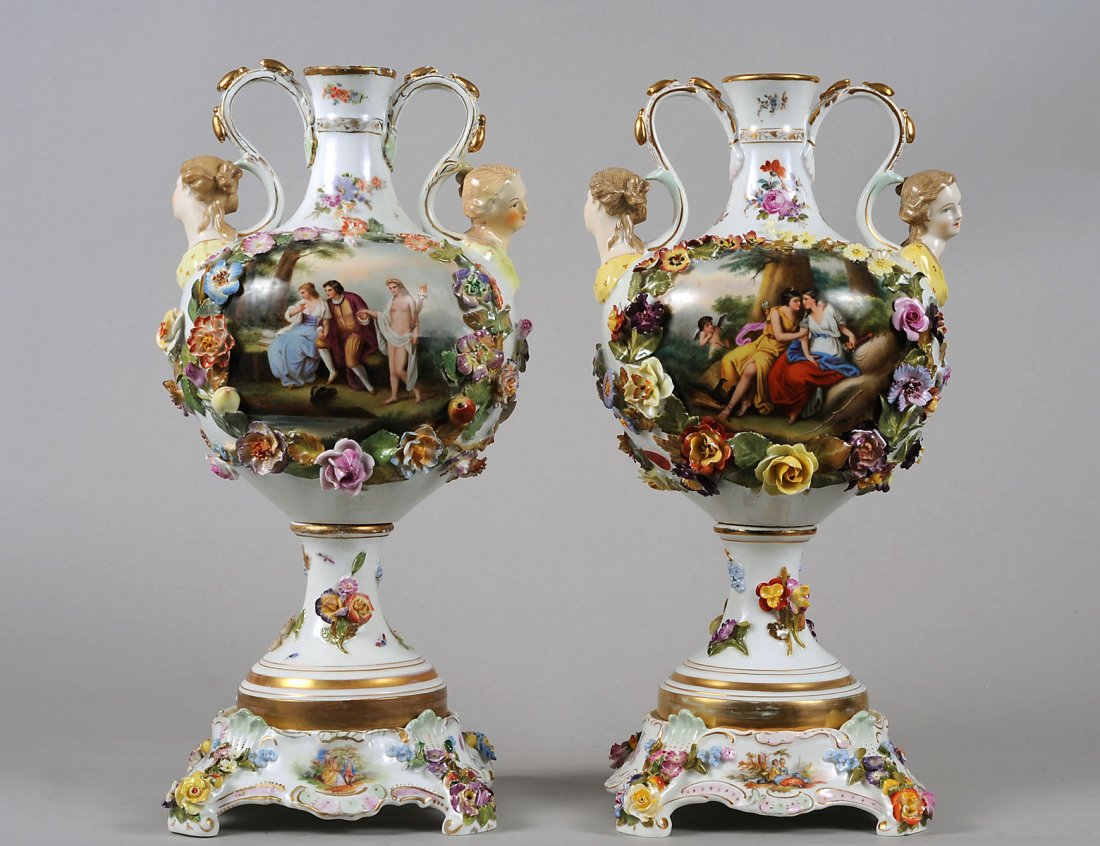 PAIR OF DRESDEN PORCELAIN VASES: German. Circa 1930. By Carl Thieme. Each molded with female mask handles and encrusted with flower garlands in high relief enclosing an allegorical scene. Height 17”. (Cond: usual chips to flowers, 