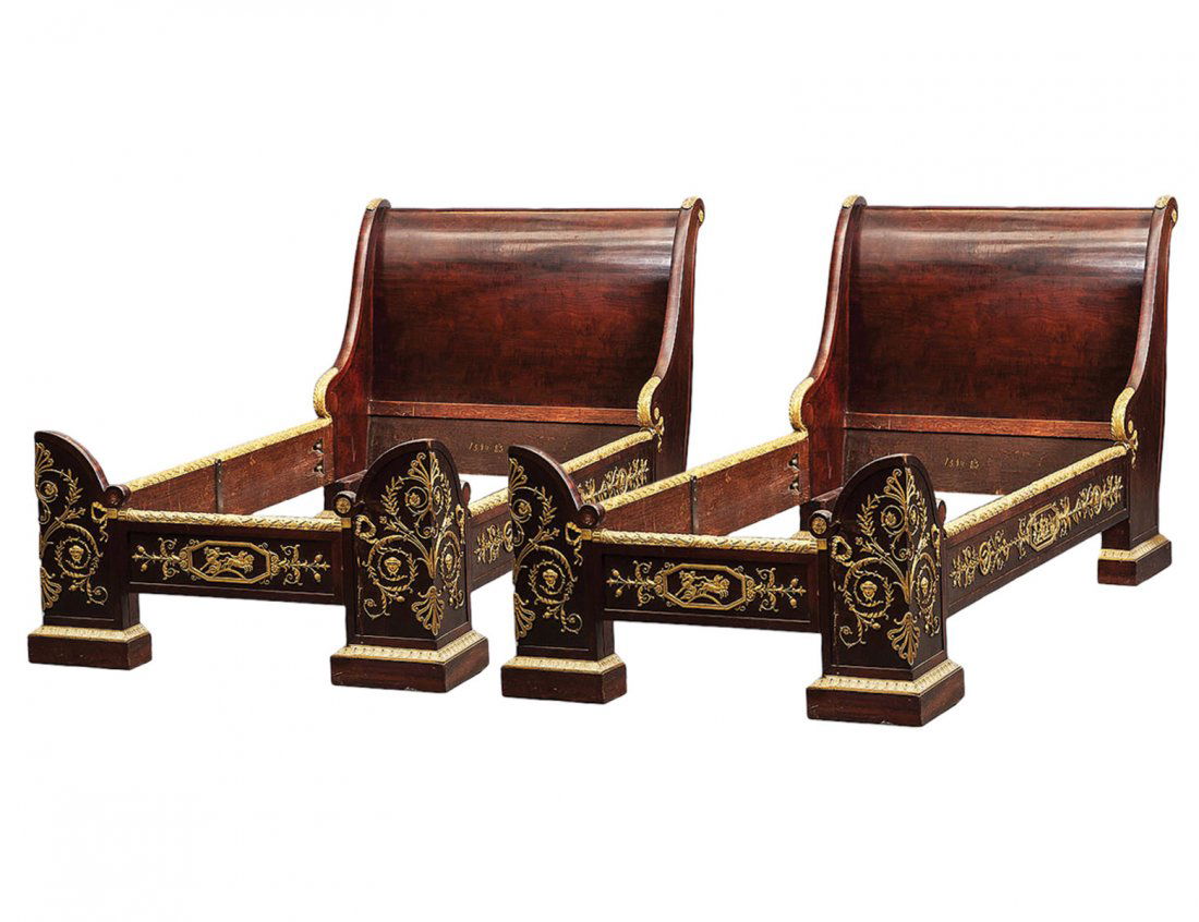 PAIR OF EMPIRE STYLE ORMOLU MOUNTED MAHOGANY BEDS: French. Late 19th Century. By Jacob Jeanselme, Paris. Each with scrolled headboard, the sides and footboard applied with anthemia, rinceaux, masks and chariots. Rails stamped Jacob Jeanselme. Length 8