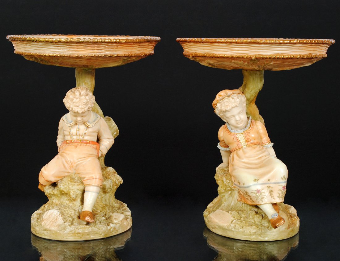 PAIR OF ROYAL WORCESTER PORCELAIN TAZZAS: English. Circa 1895. Model No. 1175. Molded as a child seated under a tree. Height 7 1/2". (Cond: one bowl and stem restored) (400/600)
