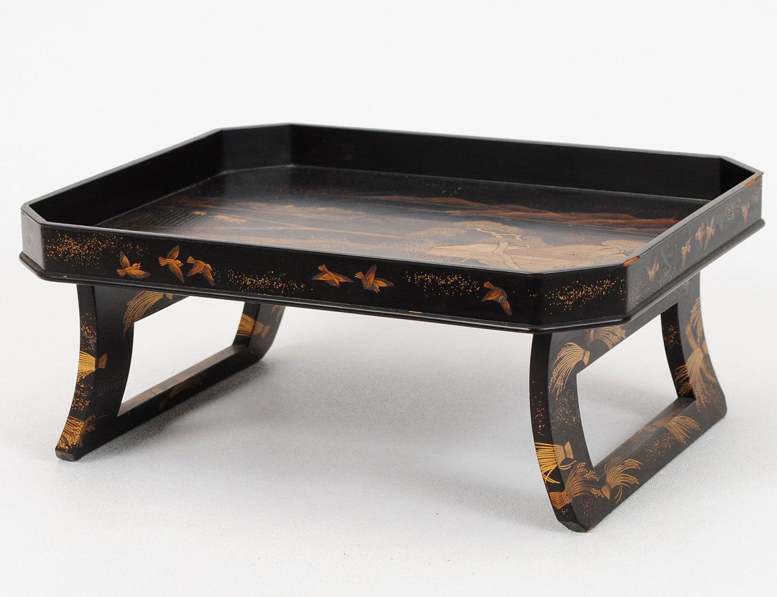 GOOD LACQUER TEA STAND: Japanese. Late Meiji-Period. Circa 1900. Of rectangular shape with canted corners on trestle supports. Decorated with raised gold depicting a landscape with a farmer plowing his field. Length 12 5/8".