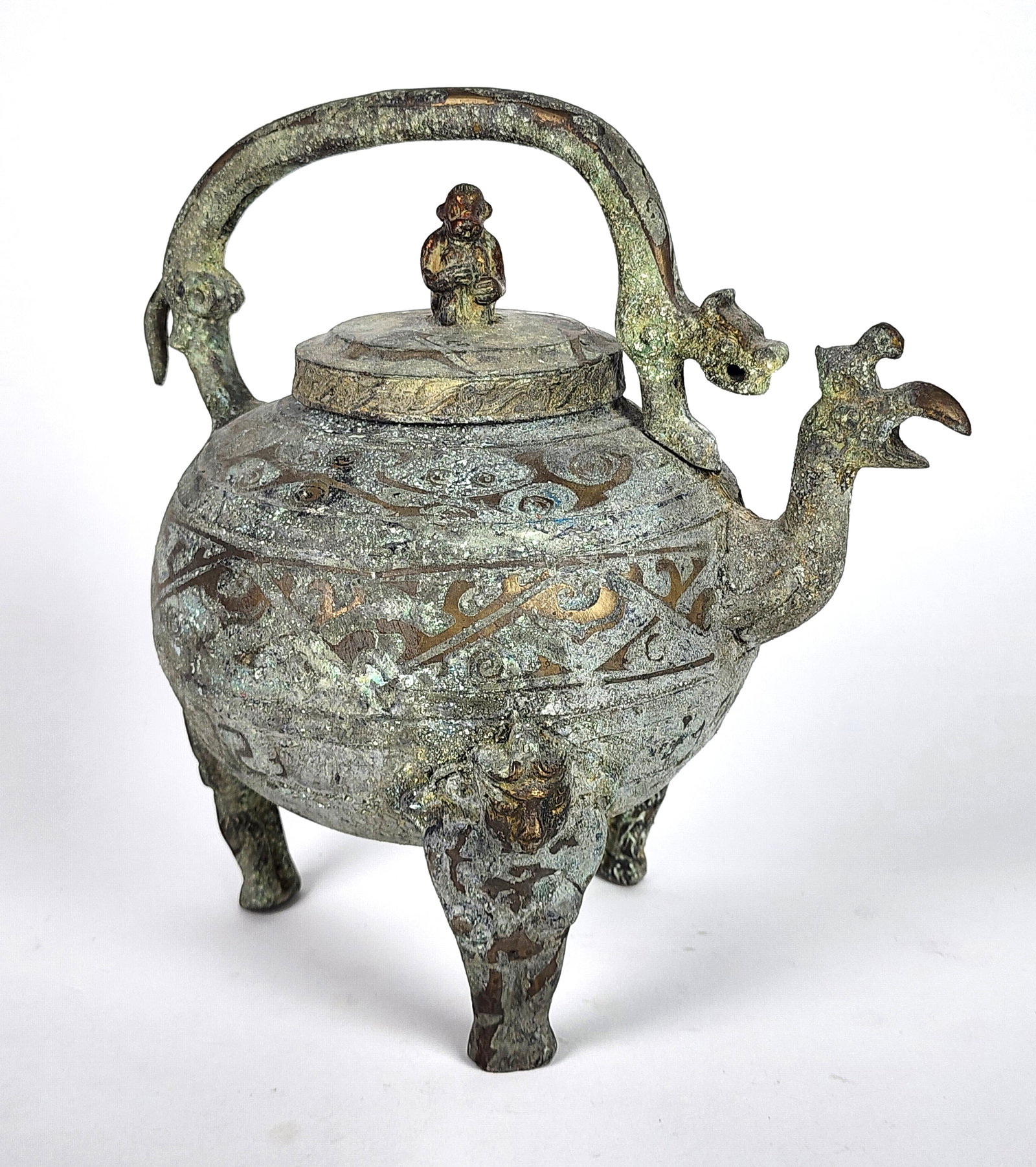 Chinese Archaic Anthropomorphic Bronze Teapot, Han Dynasty, having a bird head spout on tripod legs: Chinese Archaic Anthropomorphic Bronze Teapot, Han Dynasty, having a bird head spout on tripod legs cast with masks and a seated monkey finial and kylin handle, 10 1/4" h. 10 1/4" w. 7' d., the surfac