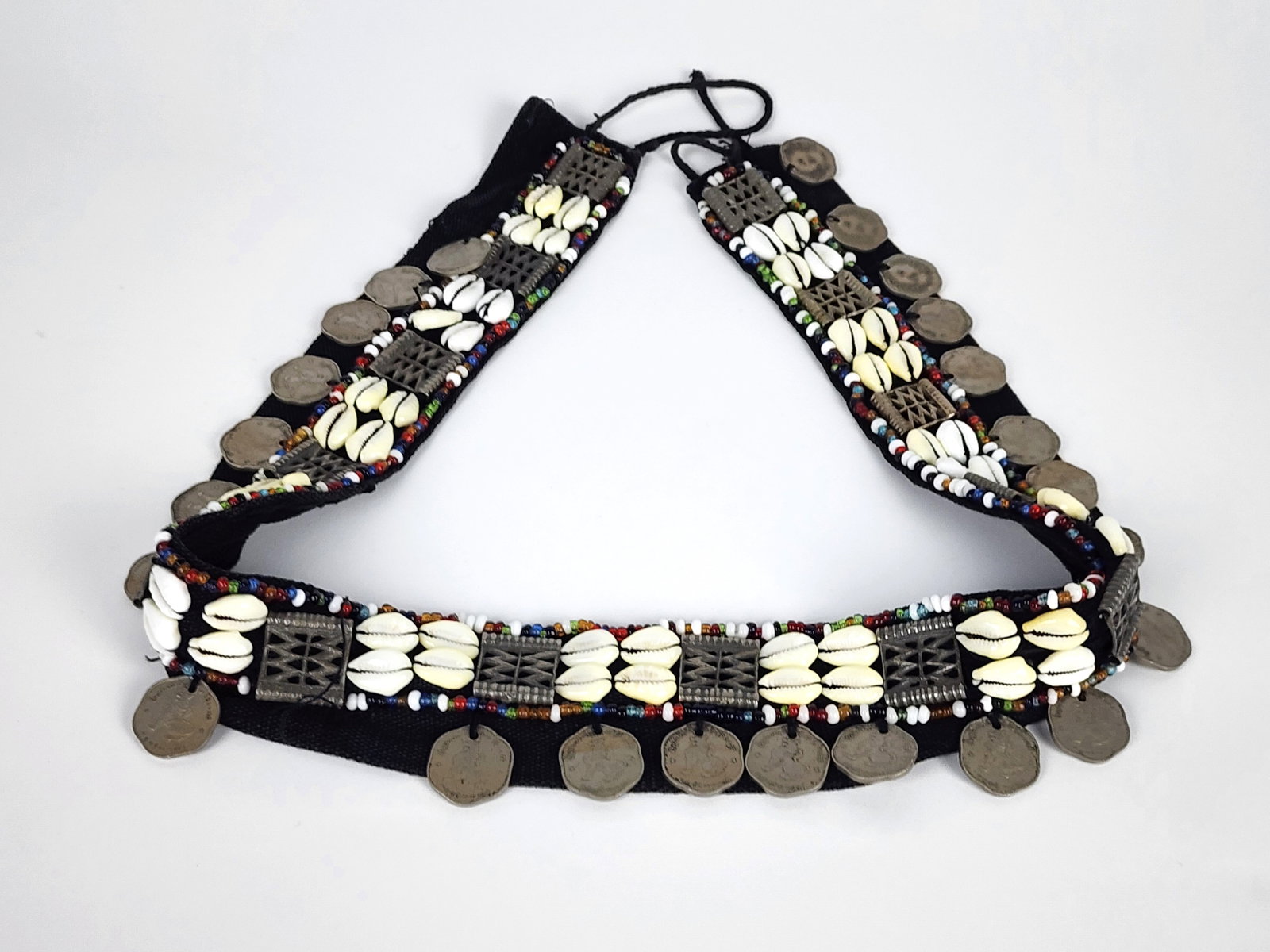 A Tibetan Woven and Beaded Belt with Coins and Cowrie Shells, 20th Century, 32 1/2" L., missing one: A Tibetan Woven and Beaded Belt with Coins and Cowrie Shells, 20th Century, 32 1/2" L., missing one coin.