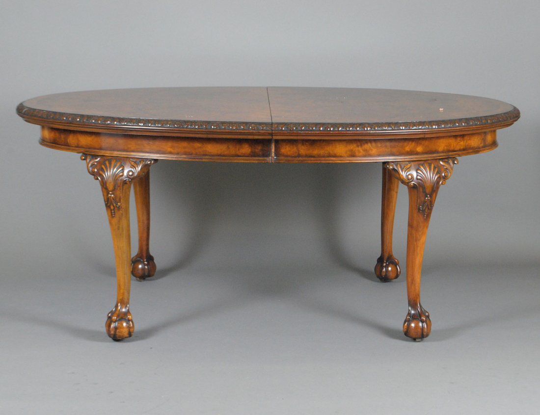QUEEN ANNE STYLE WALNUT AND BURL DINING TABLE: The cross banded oval top with crank opening above the molded frieze, raised on shell carved cabriole legs ending in pad feet. Height 30 1/4". Width 70 1/2". Depth 47". With one extension leaf measuri