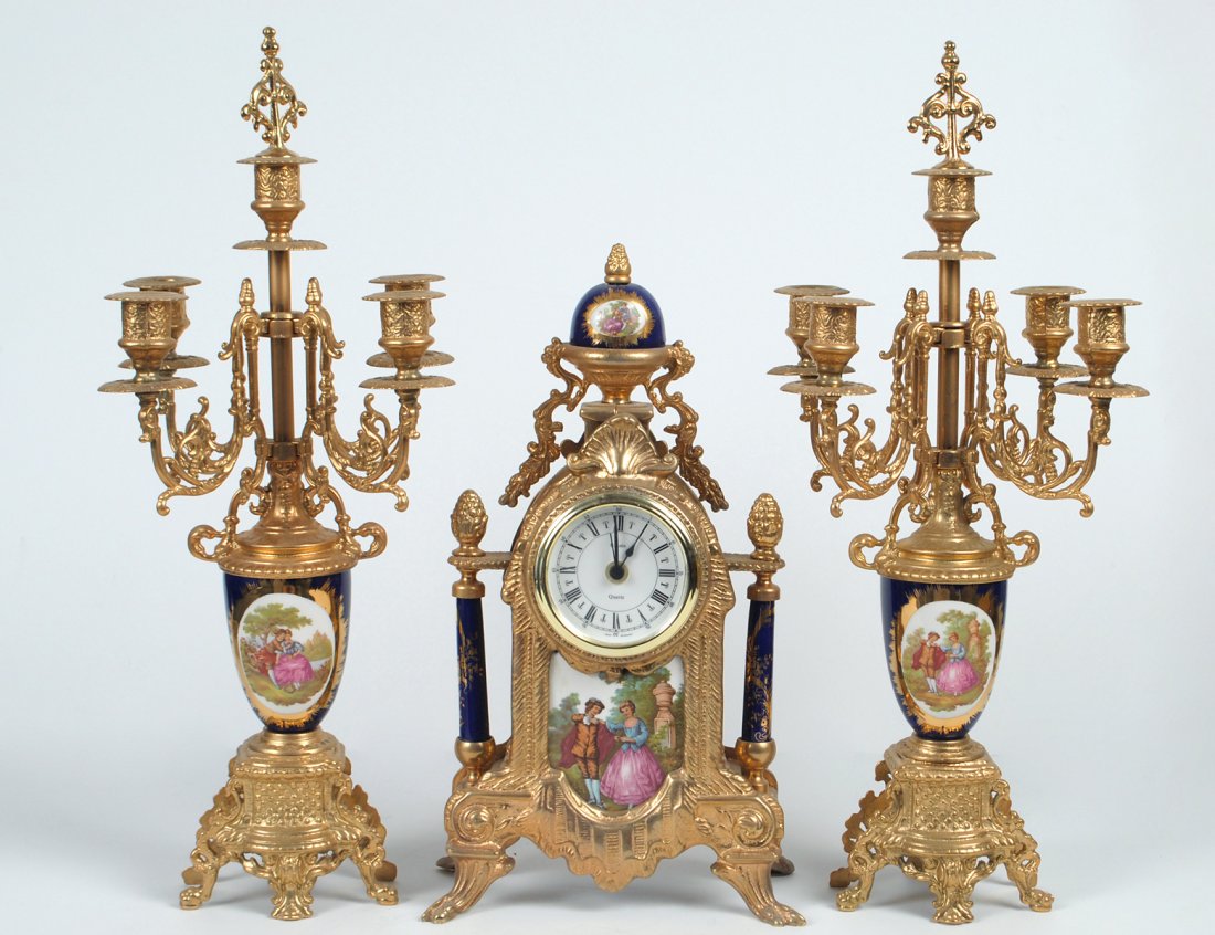 THREE PIECE BRASS AND PORCELAIN CLOCK GARNITURE: Italian. With German quartz movement. Comprising: mantel clock and a pair of five light candelabras. Height of clock 14 3/4". Height of candelabras 19 3/8". (400/600)
