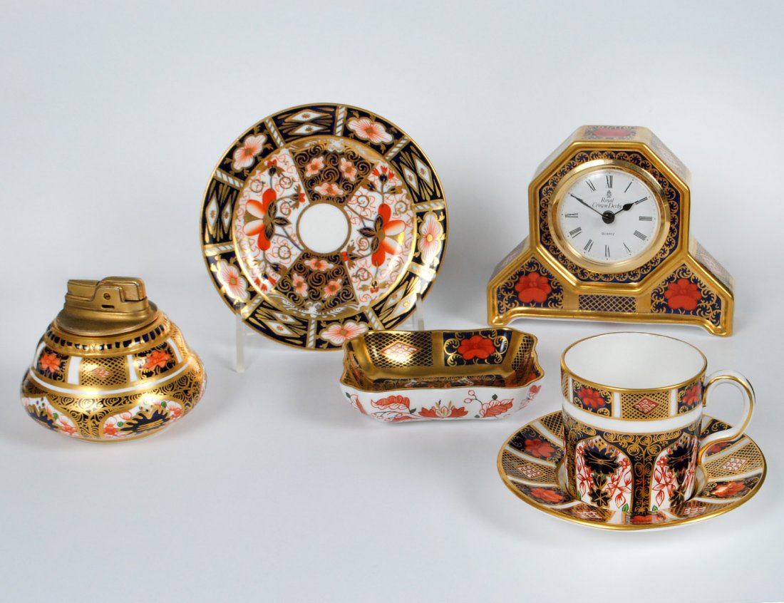 GROUP OF SIX ROYAL CROWN DERBY PORCELAIN ARTICLES: English. Comprising: table clock, lighter, small dish, coffee can and stand, and butter pad. (150/200)