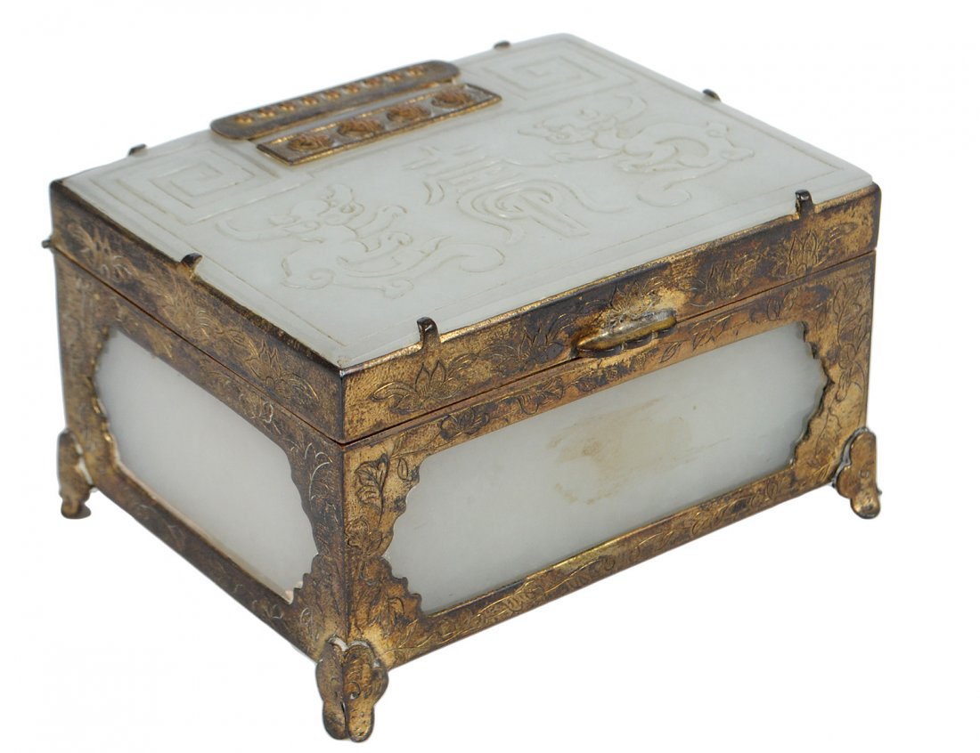 FINE WHITE JADE AND BRASS BOX: Chinese. Circa 1900. The hinged lid carved with dragons and a symbol, applied with a silver plaque on the reverse, the box with jade sides. Length 3 1/2". (1000/1500) Note: This lot is being re-offere