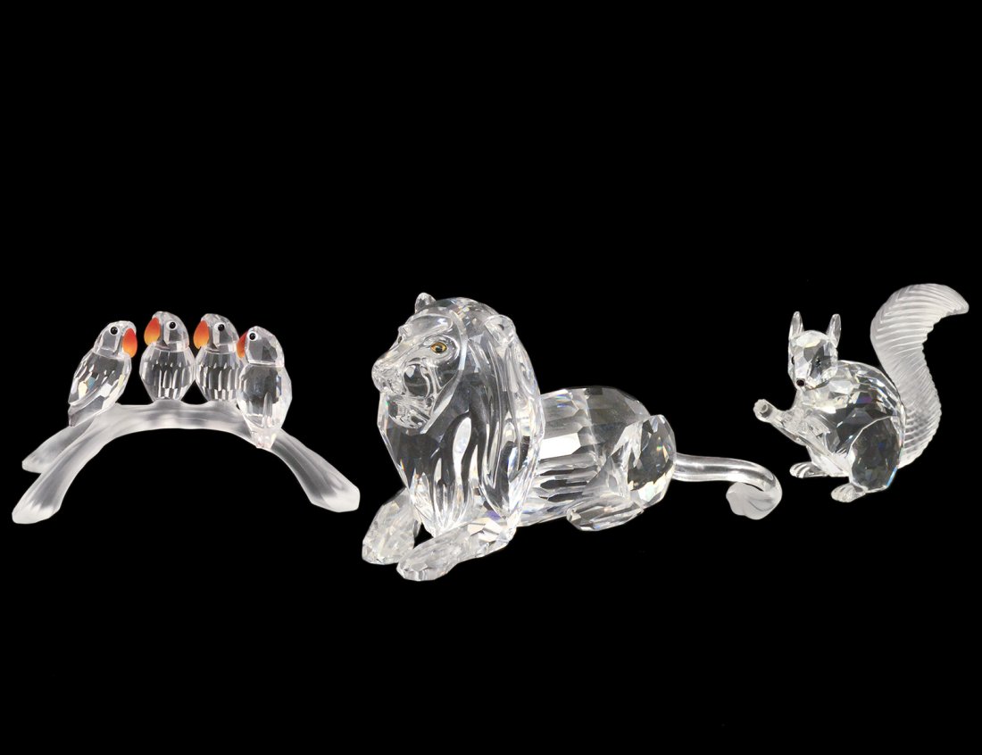 THREE SWAROVSKI CRYSTAL FIGURES: Comprising: recumbent lion, seated squirrel and parrots on a branch. (150/200)