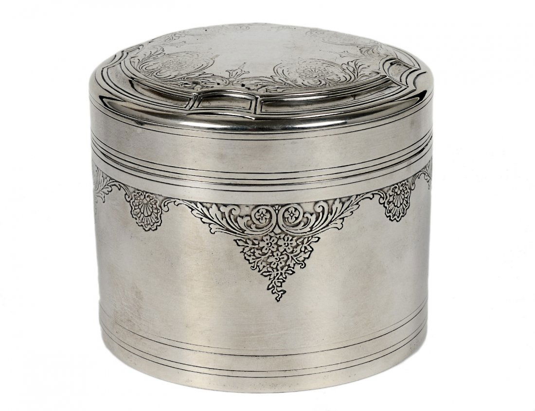 TIFFANY & CO. STERLING SILVER BOX AND COVER: American. 1907-1938. Of cylindrical shape engraved with foliate decoration. Height 2 ¾”. (7 oz) (200/300)