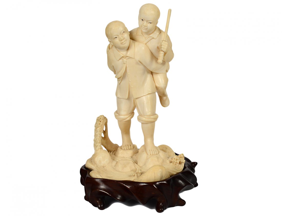 WELL CARVED IVORY GROUP: Chinese Republic. Of two boys crossing a creek. Height 6". On a carved wood stand. (100/500)