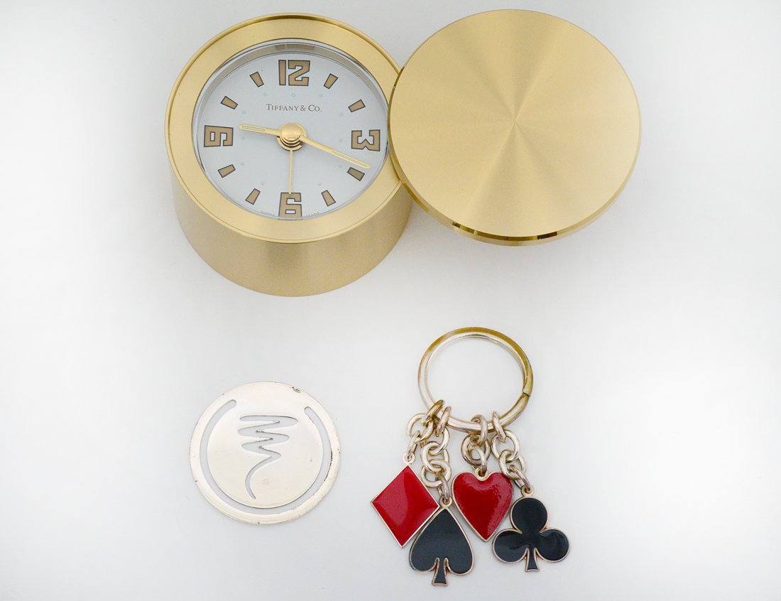 GROUP OF THREE TIFFANY & CO. ARTICLES: American. Comprising: brass travel clock with Swiss movement, diameter 2 3/8"; Paloma Picasso design sterling silver money clip; and a key chain. (200/300)