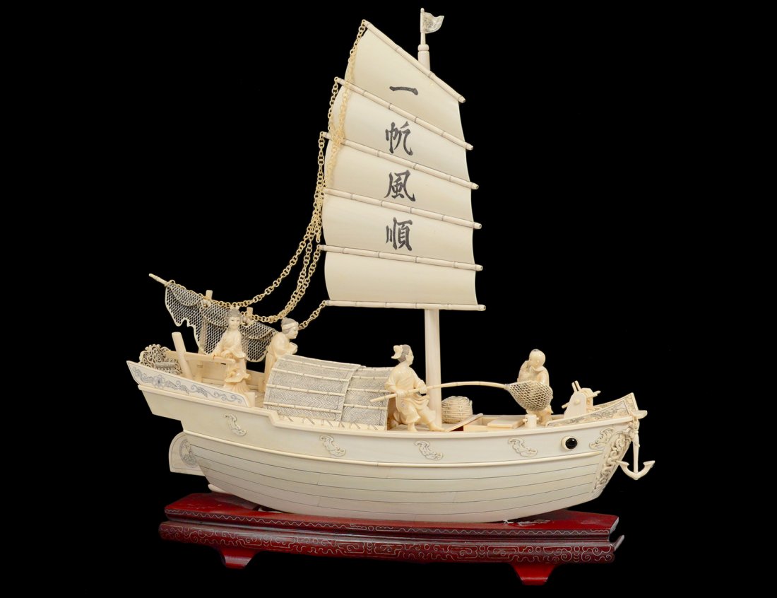 IMPRESSIVE IVORY JUNK: Chinese. Signed. Under full sail, the deck with four figures, baskets and nets with moveable anchor. Height 21 1/4". Length 22 1/2". On a silver inlaid wood stand. (5000/6000)