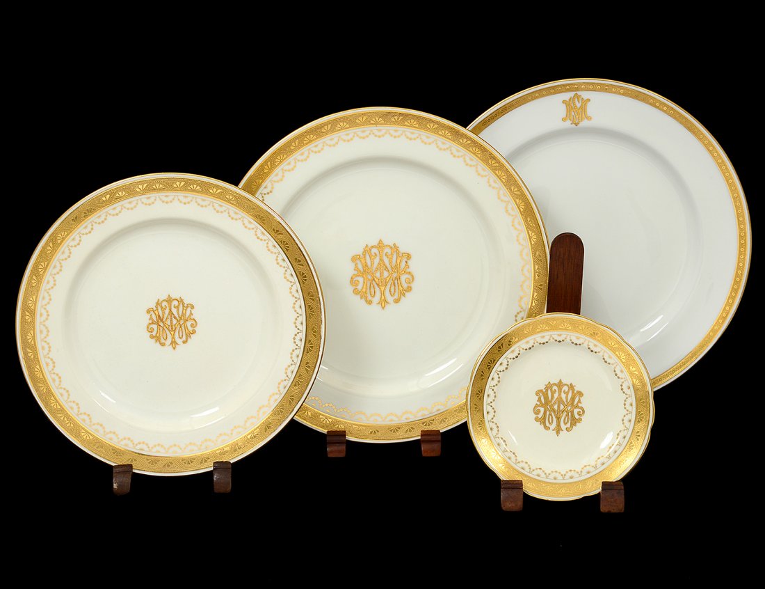 SIXTY PIECE MINTONS PORCELAIN PART DINNER SERVICE: English. 20th Century. Comprising: twenty-four dinner plates, eleven salad plates, eleven bread and butter plates and fourteen service plates. Each with a gilt conjoined monogram and border. (800/1200