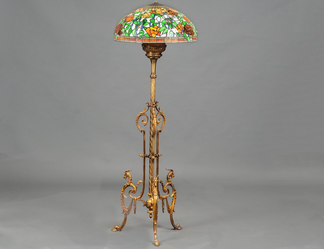 EMPIRE STYLE GILT BRONZE KEROSENE FLOOR LAMP: Late 19th Century. On ram's supports, with a 22 1/2" leaded shade. Height 65". (600/900)