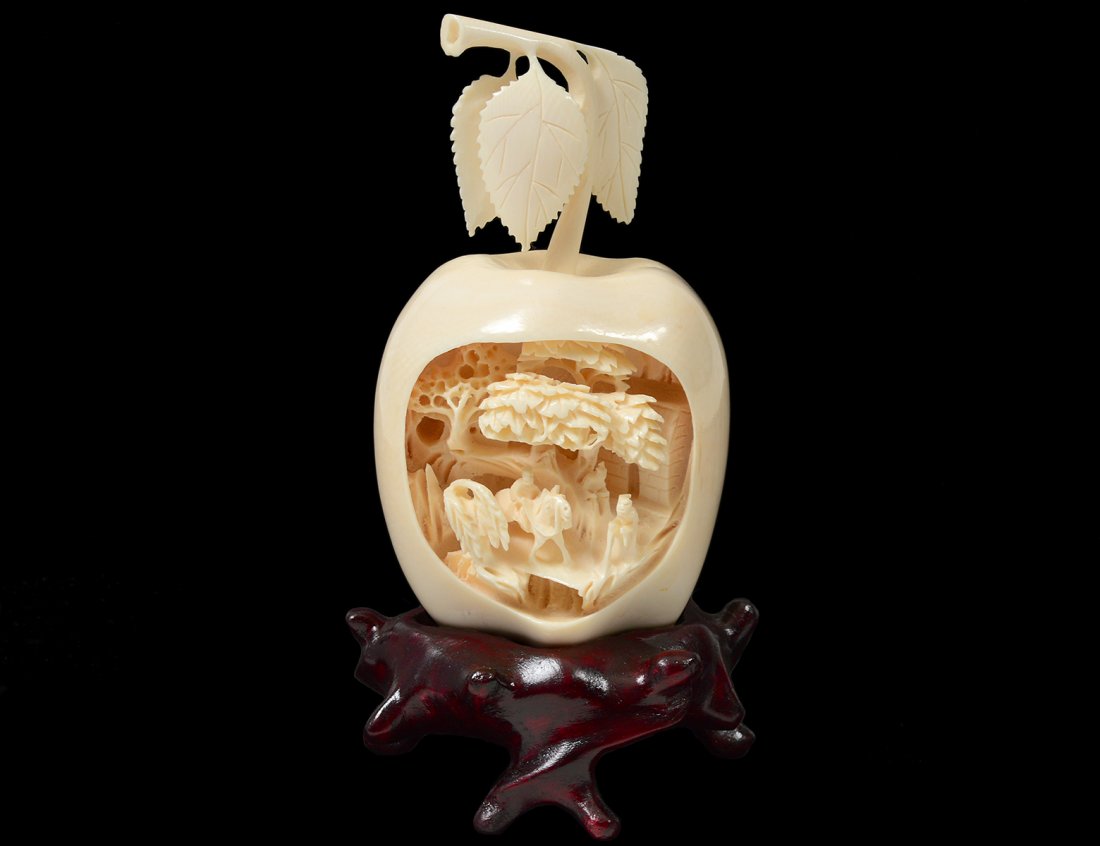 CARVED IVORY STUDY OF AN APPLE: Chinese. Incarved with a village scene. Height 4 1/4". With wood stand. (100/150)