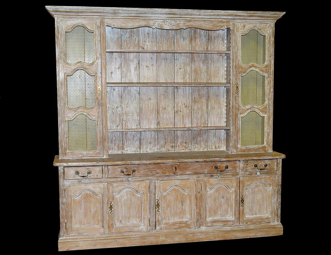 PROVINCIAL STYLE PICKLED PINE HUTCH: In two parts. The upper with open shelves flanked by grille doors, the lower with three frieze drawers and six paneled cupboard doors. Height 94". Width 96 1/2". Depth 22". (1000/1500)