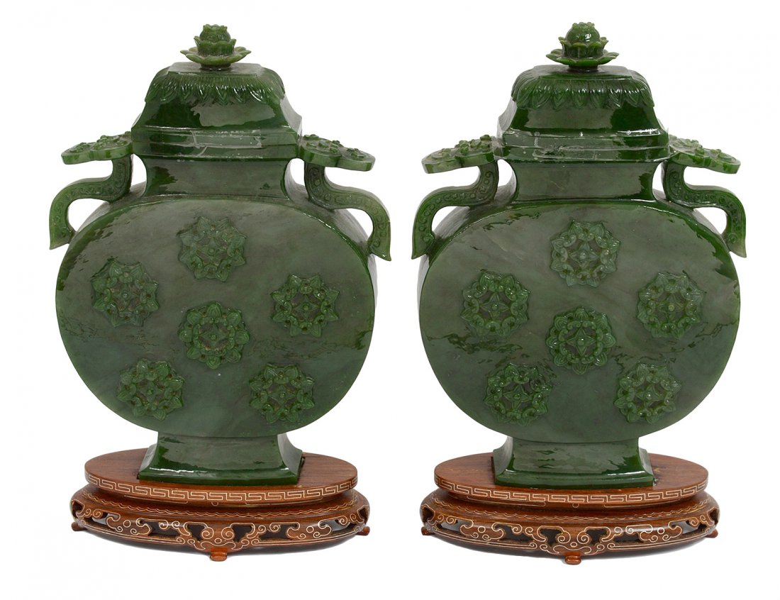 PAIR OF CARVED SPINACH JADE VASES AND COVERS: Chinese. Each of moon flask shape, carved with scepter handles and blossoms. Height 10 1/2". With wood stands. (1000/1500)