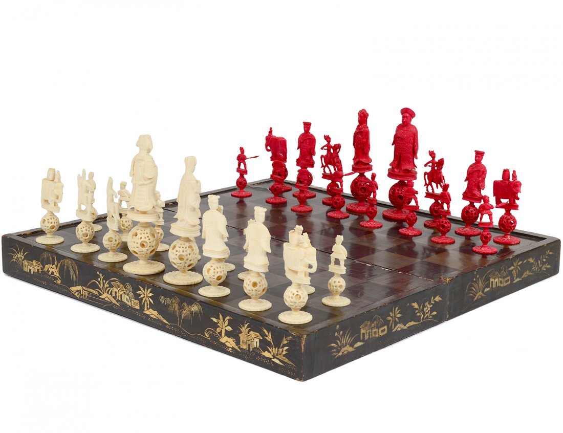 CARVED AND STAINED IVORY FIGURAL CHESS SET: Chinese. One side natural, the other stained red. Each figure standing on a concentric ball. Height of king 5 1/8". Height of pawn 2 3/8". With lacquered board box. (600/800)