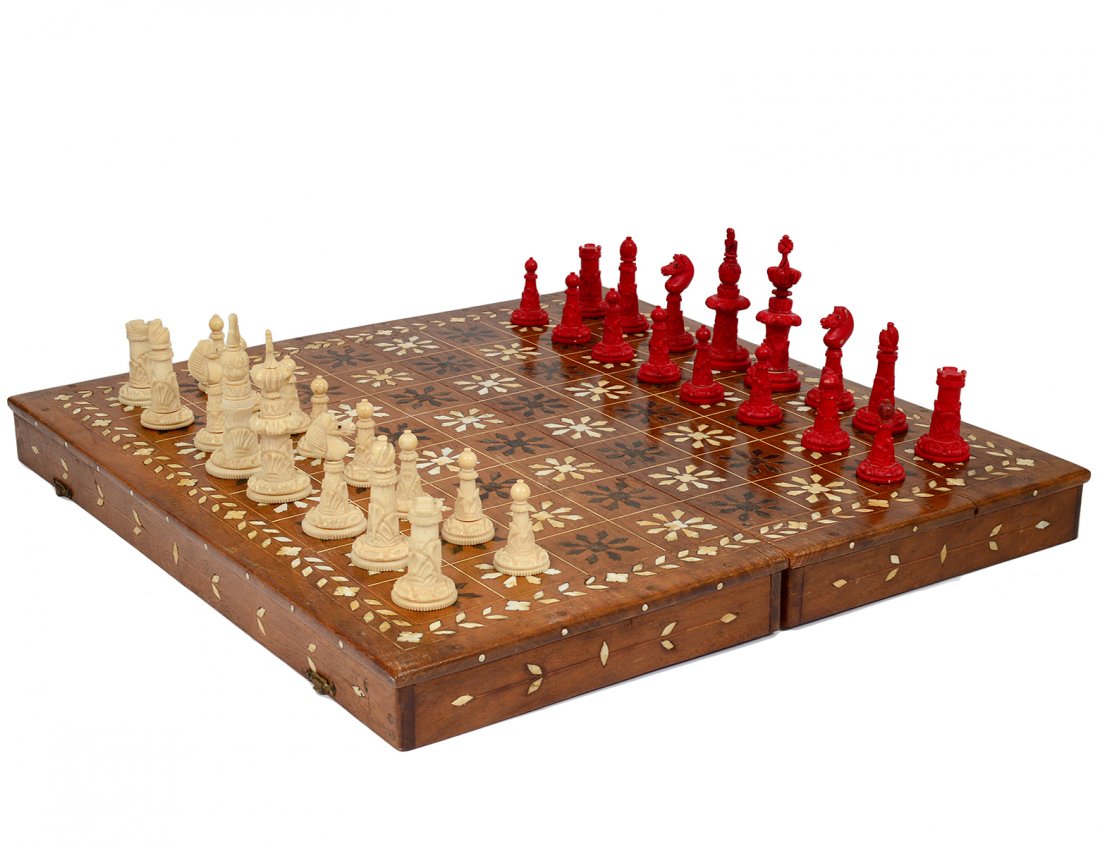CARVED IVORY CHESS SET: One side natural, the other stained red. Height of king 3". Height of pawn 1 1/2". (Cond: minor losses) With bone inlaid board box. (300/500)