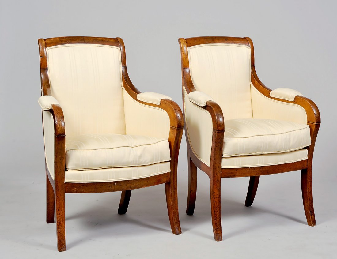 PAIR OF EMPIRE WALNUT BERGERES: French. Circa 1820. Each with padded backrest, loose seat cushion and raised on saber legs. (400/600)