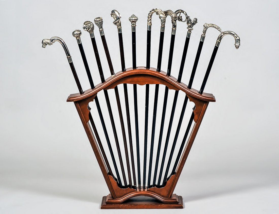 SET OF TWELVE SILVER PLATED HANDLED WALKING CANES: With a fan shaped wood stand containing the canes. (Cond: one stick restored) (300/400)