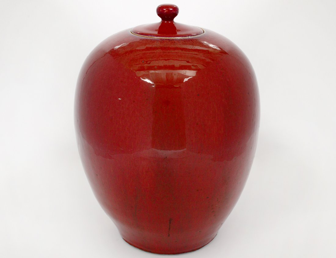 SANG DE BOUF GLAZED PORCELAIN JAR AND COVER: Chinese. Of ovoid form. Height 12 1/4". (150/200)
