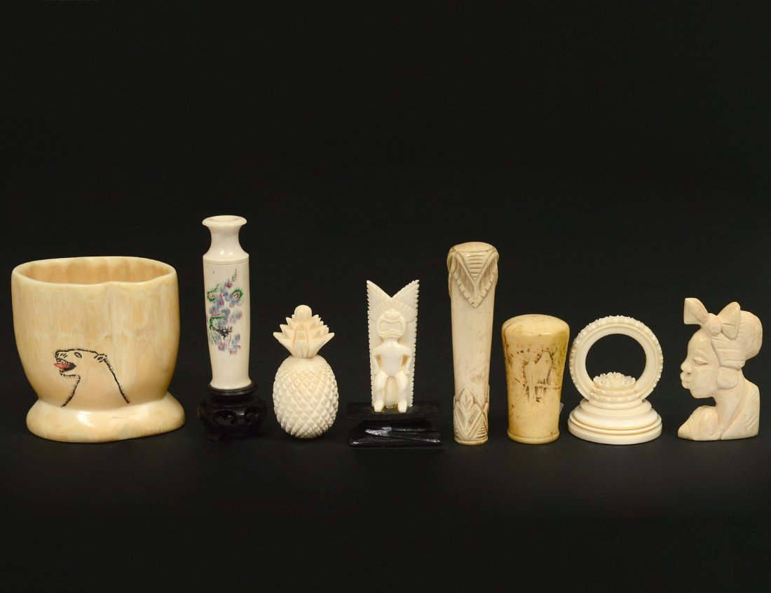 GOURP OF SEVEN ASSORTED IVORY AND BONE ARTICLES: Various origins. Comprising: Eskimo totem figure and jar, tribal mask of a female, etched bud vase, pineapple, ornament and a parasol handle. (100/150) NOTE: DOMESTIC AND INTERNATIONAL SHIPPING IS NOT