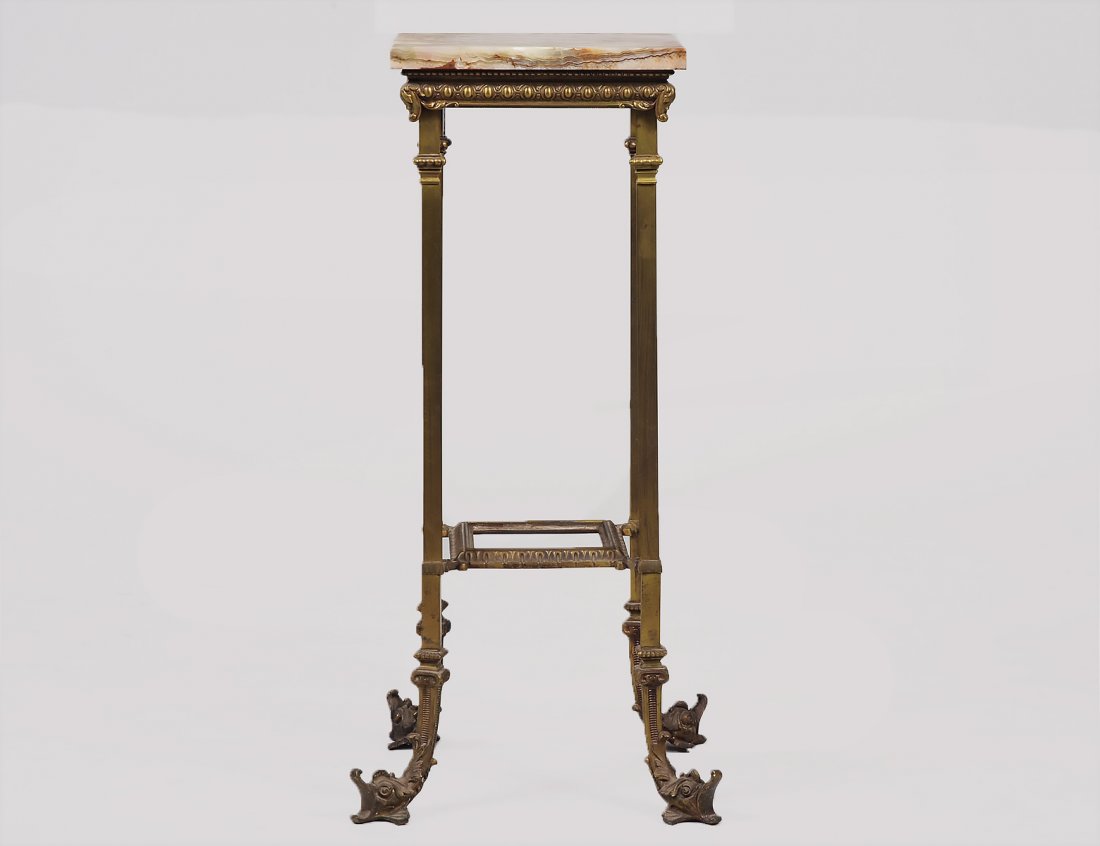 ONYX AND GILT BRASS PEDESTAL: French. Circa 1920. With a glass inset platform stretcher, the straight legs ending in grotesque serpent head's feet. Height 32". Width square 15". (150/250)