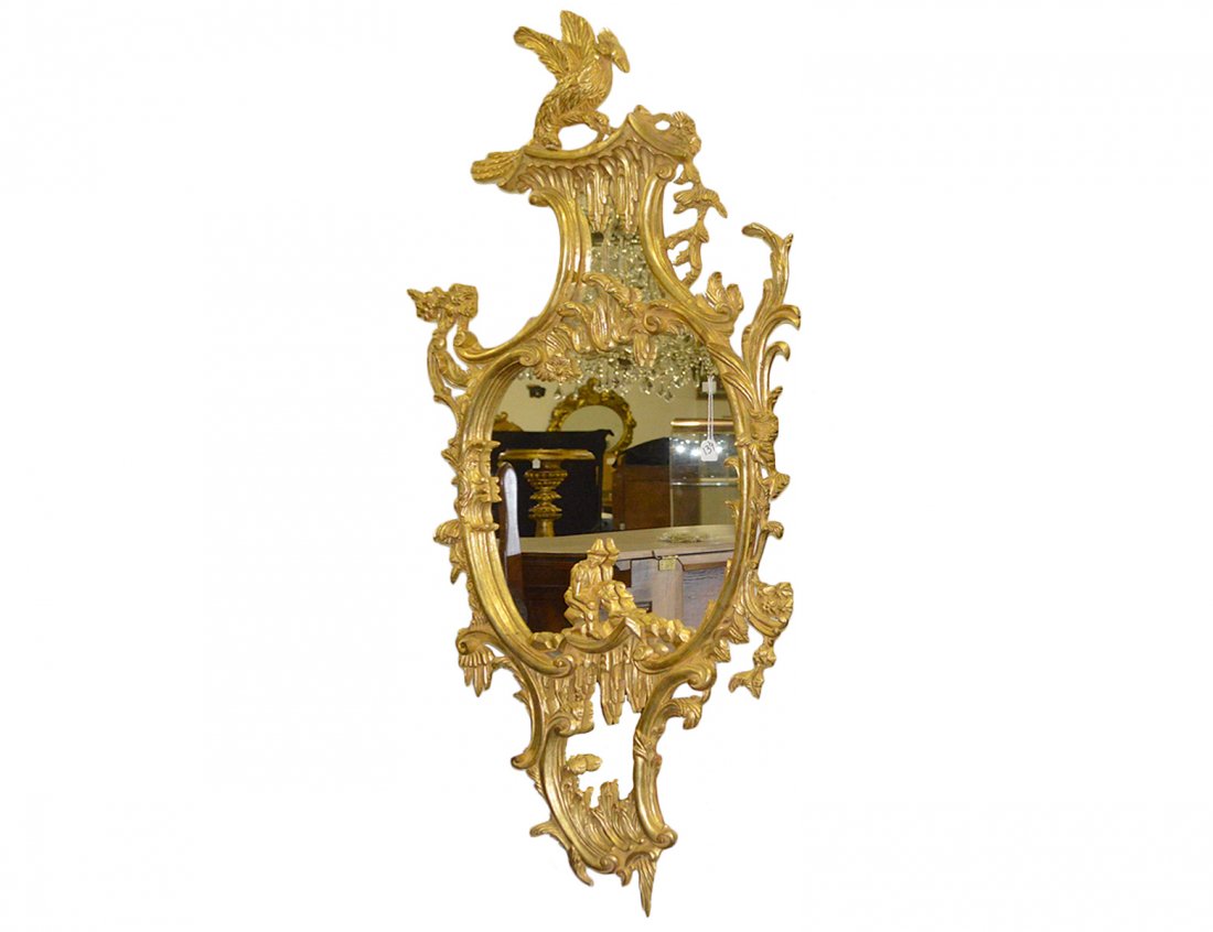 “CHINESE CHIPPENDALE” STYLE GILT WOOD MIRROR: Modern. In the manner of Thomas Chippendale. The tripartite mirror plate within an elaborately carved surround, the central plate centered by a ‘Chinaman’ seated upon rockwork, the crest with a di