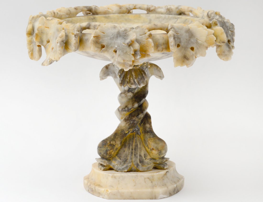 ALABASTER COMPOTE: Italian. 20th Century. The grape leaf enclosed bowl above a dolphin standard, raised on a tripartite base. Height 9 ¼”. (50/75)