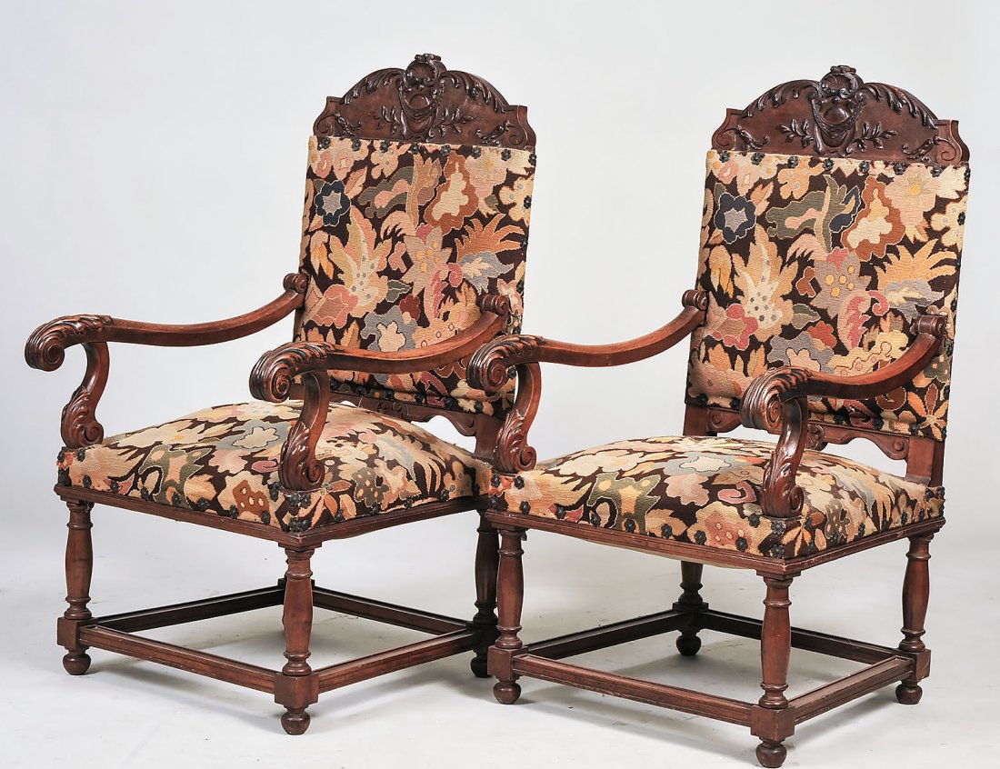 PAIR OF LOUIS XIII STYLE WALNUT ARMCHAIRS: French. Circa 1880. Each padded backrest below a carved crown, flanked by downcurved leaf capped armrests, the padded seat on turned legs joined by a box stretcher. (150/200)