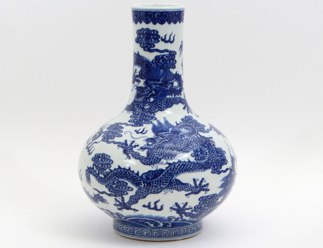 CHINESE BLUE AND WHITE PORCELAIN BOTTLE FORM VASE: 20th Century. In a Ming Style, the underside with an under-glazed character mark. Generously potted and decorated with multiple Imperial dragons floating amidst clouds, with an upper Ruyi and lower Gr