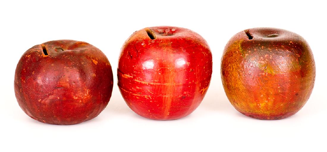 Lot of Three: Redware Figural Apple Banks: Three Painted Redware Apple Banks, late 19th century, each molded in the form of an apple with original red-painted surface and carved slot. All with typical wear. One with shallow chipping to slot. H