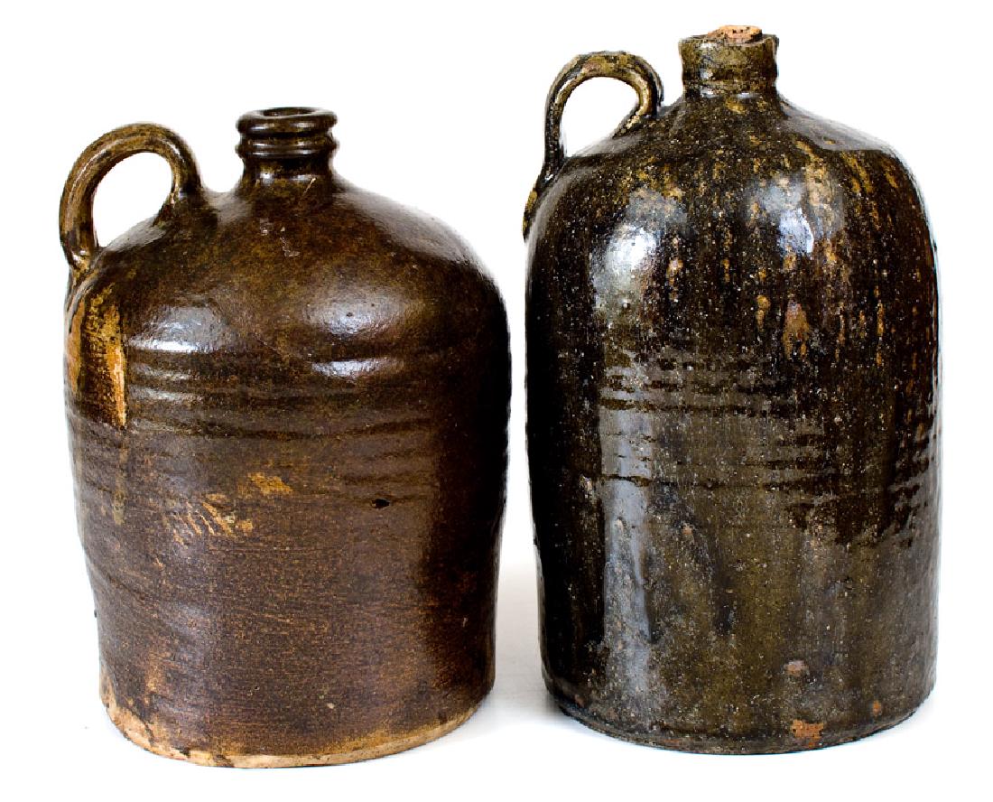 Lot of Two: Southern Pottery Jugs (Edgefield, SC and: Two One-Gallon Alkaline-Glazed Stoneware Jugs, Southern U.S. origin, second half 19th century, a cylindrical jug with tooled shoulder and streaky brown alkaline glaze, impressed "O" on handle, Edgefie